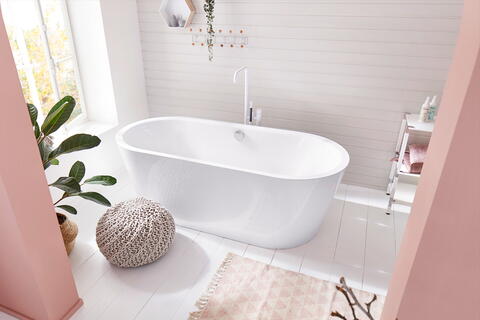 Pinkes Badezimmer mit freistehender Badewanne, Teppich und weiteren Deko-Elementen