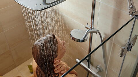 Frau steht in der Dusche und wäscht sich die Haare