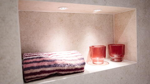 Nische über der Badewanne mit Handtuch und Teelichtern
