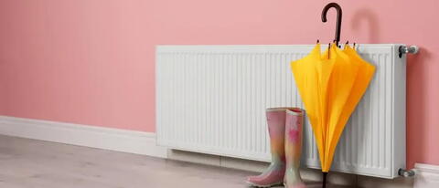 Heizkörper mit Regenschirm und Gummistiefeln