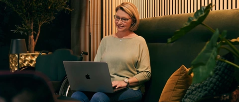 Frau sitzt auf dem Sofa mit Laptop