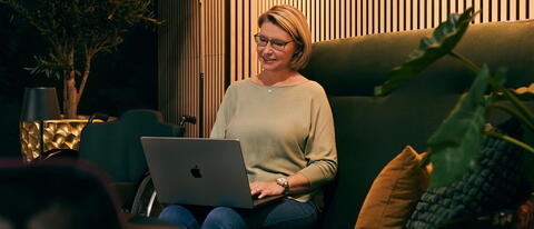 Frau sitzt auf dem Sofa mit Laptop