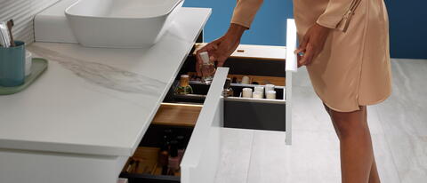 Frau öffnet Badezimmerschublade mit Beautyprodukten