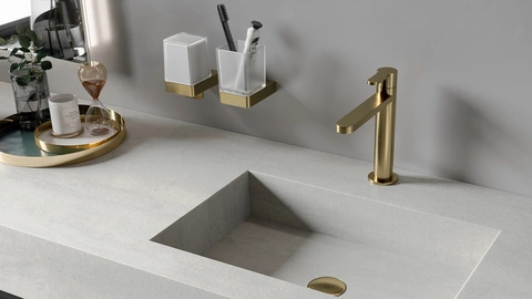 Nahaufnahme eines hellen, eingelassenen Waschbeckens und goldenen Edelstahlarmaturen