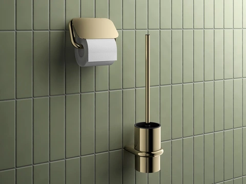 Elegant inszenierter Toilettenpapierhalter und WC-Bürstenset in glänzend goldener Ausführung vor einer edlen grün gekachelten Wand – ein luxuriös gestaltetes Detail in einem modernen Badezimmer/ HEWI/ S 480