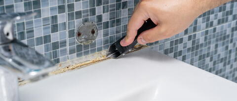 Dreckige Fuge wird von einer Hand mit Fugenreiniger gereinigt