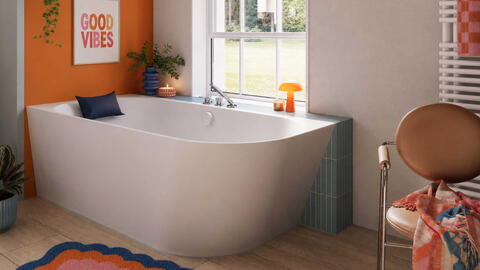 Badewanne vor einer orangenen Wand mit ausgewählten, farbigen Dekoartikeln