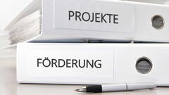 Zwei weiße Ordner liegen aufeinander, jeweils beschriftet mit "Projekte" und "Förderung"